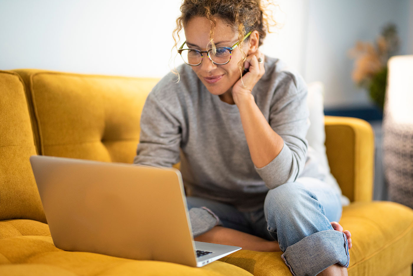 zur BAHN-BKK wechseln Frau sitzt auf dem Sofa vor Laptop