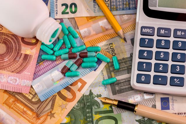 Euroscheine, auf den Kapseln, Stifte und ein Taschenrechner liegen